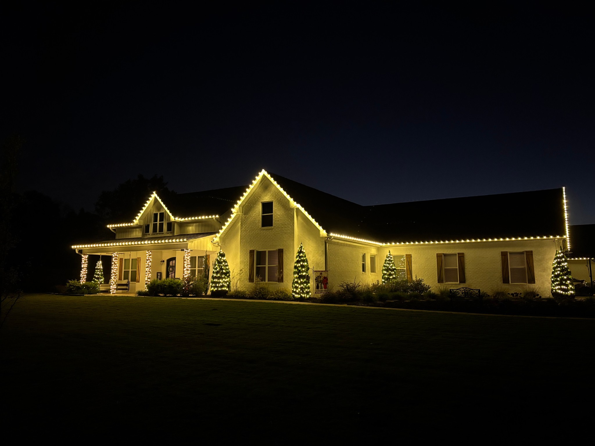 Alternate angle of the Estate display showing warm white lighting across the home, columns, and trees